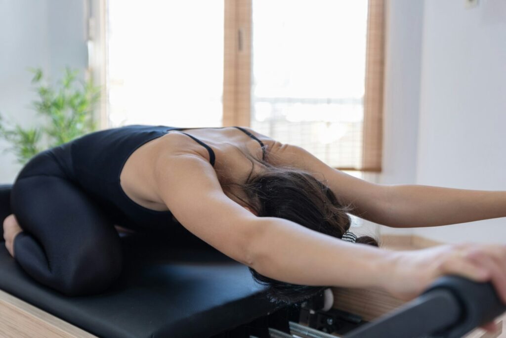 Young woman exercising on pilates reformer bed